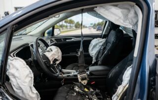 A torn and malfunctioning seat belt inside a sedan during a forensic crash inspection.