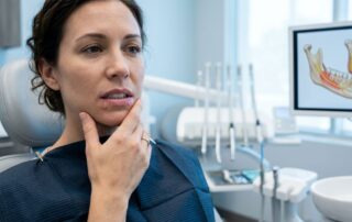 Patient touching a numb lower lip during a dental examination.