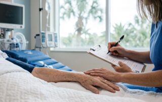 A nurse documents a patient’s forearm beside a pressure-relieving mattress.