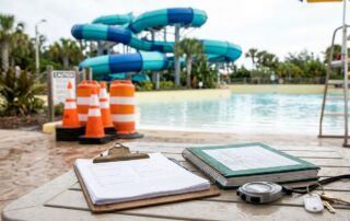 A clipboard and maintenance records sit on a wet table near a waterslide.