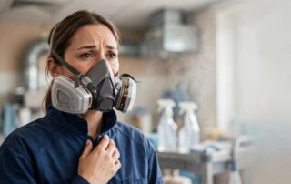 A concerned cleaner wearing a respirator in a commercial workplace.
