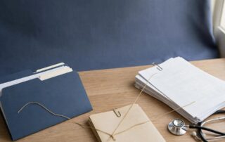 An evidence folder, medical records, service documents, and a stethoscope arranged on a desk.